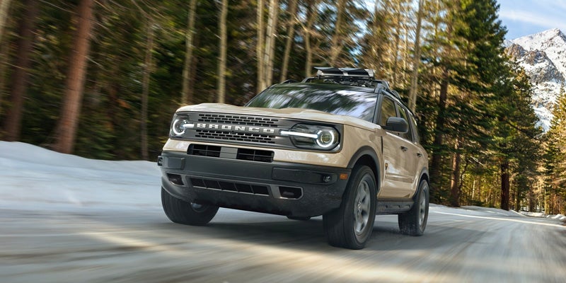 Tan 2024 Ford Bronco Sport traversing rugged, wooded landscapes